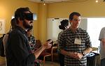 一个虚拟现实演示，左边一个人看着镜头外的东西，另一个人戴着VR眼镜. 